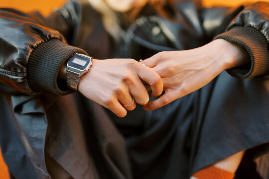 Hands Holding a Watch and Rings in a Casual Setting