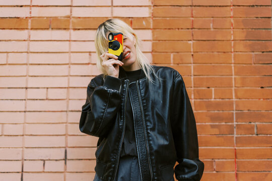 Person Holding a Camera in Front of a Brick Wall