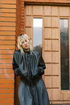 Person Stands by a Brick Wall Near a Wooden Door in the City