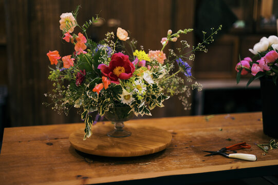 bouquet being arranged on wooden table inside floral studio