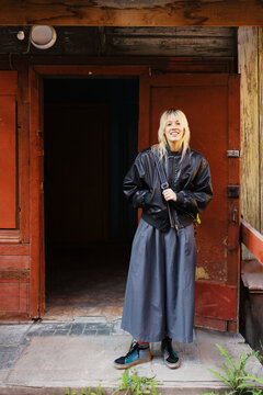 Young Woman Stands at Door of Old Building in Urban Area