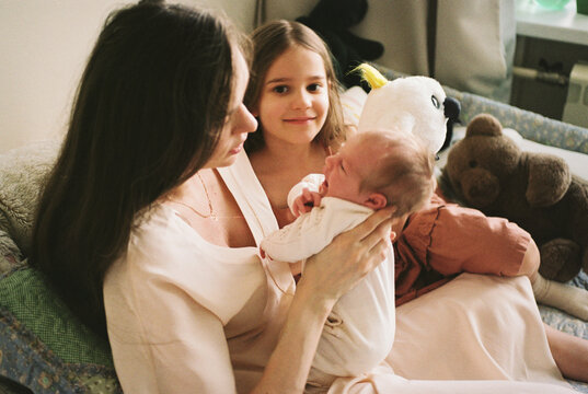 Mother Holding Newborn with Daughter at Home