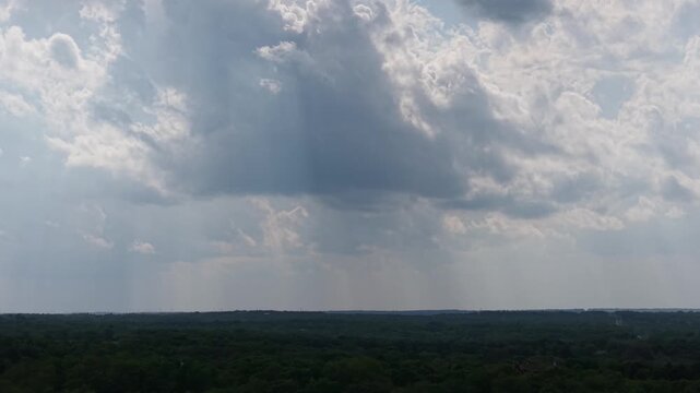 Aerial push forward toward rain shafts over forest Oklahoma spring