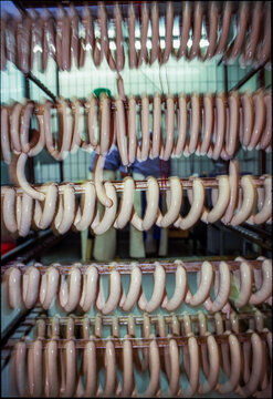 Many sausages hang in a butcher shop