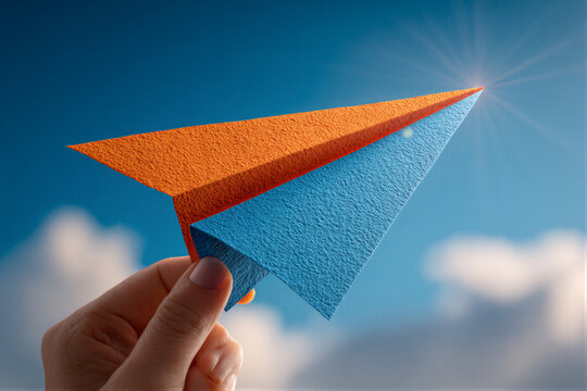 Hand Silhouette Releasing Vibrant Origami Paper Airplane Against Deep Blue Sky. Dramatic Backlighting With Tyndall Effect Lens Flare. Clean Copy Space For Corporate Vision And Startup Inspiration. 8K