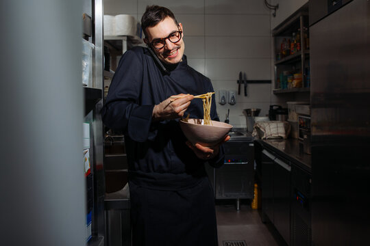 Chef Talking on Phone While Serving Noodles in Kitchen
