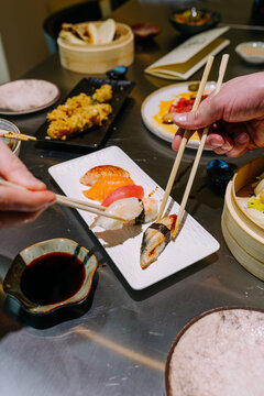 Hands Picking Nigiri Sushi With Chopsticks At Dinner