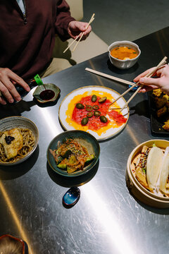 Friends Sharing Japanese Sashimi and Small Plates At Table