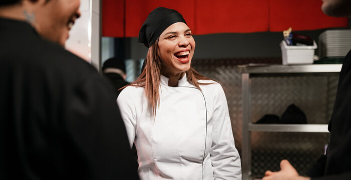 Happy Female Chef Laughing With Kitchen Team