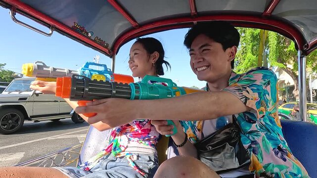 Young Couple Celebrating Songkran Festival with Water Guns in Tuk Tuk