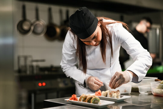 Female Chef Plating Sushi in Professional Kitchen