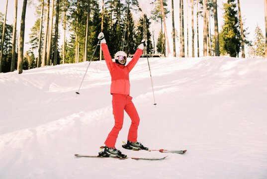 
Joyful Skier in Pink Suit With Arms Raised on Snowy Slope
