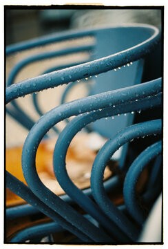 Rain droplets on blue metal cafe chairs