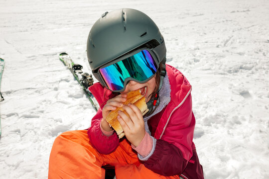 Child Enjoys a Sandwich During a Ski Break on a Snowy Mountain