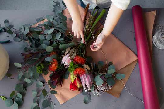 Florist Arranging Protea Bouquet on Table