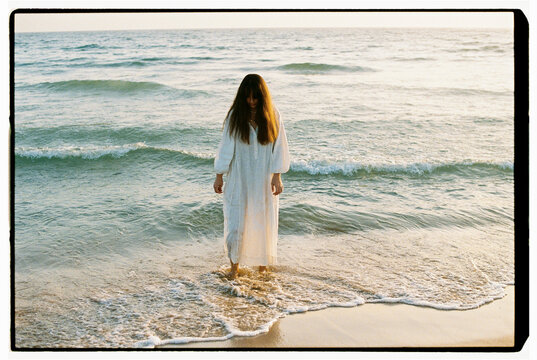 Woman in white dress walking out of sea