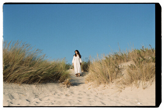 Woman walking along sandy dune path