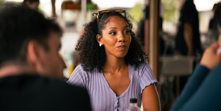 Woman with friends talking at restaurant table and enjoying lunch
