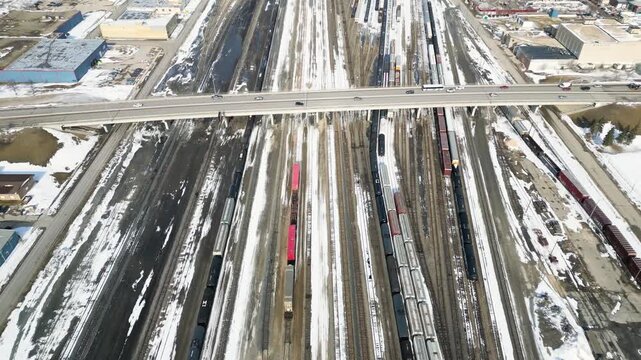 Drone shot tilting up from a train yard to reveal an industrial area of Winnipeg Manitoba Canada during winter daytime