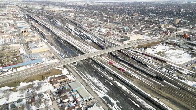 Orbiting timelapse drone shot of a bridge above an industrial train yard with fast moving traffic below