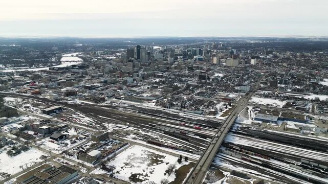 Wide drone shot of downtown Winnipeg Manitoba Canada in winter with a large industrial train yard in the foreground