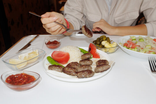 A young woman takes a cutlet with a fork