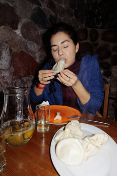 A young woman eats khinkali.