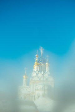 Church stands under clear sky with water mist in front