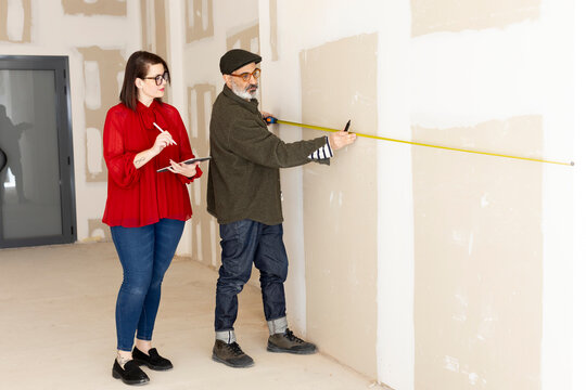 Interior designer and constructor taking measurements 