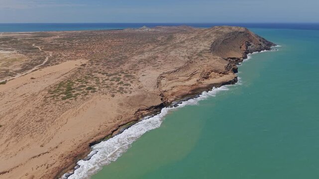 Spectacular aerial footage of Cabo de la Vela&rsquo;s rugged coastline in La Guajira, Colombia, showcasing dramatic desert cliffs, turquoise Caribbean waters, and sunny, cloudless skies. Crisp drone video.