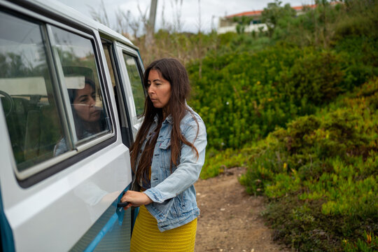 Indigenous woman opening side door of old Camper van 
