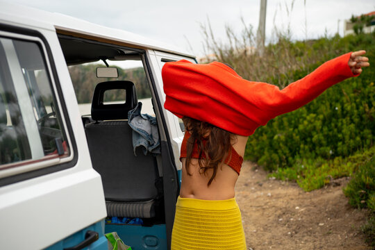 Indigenous woman getting changed by old Camper van 