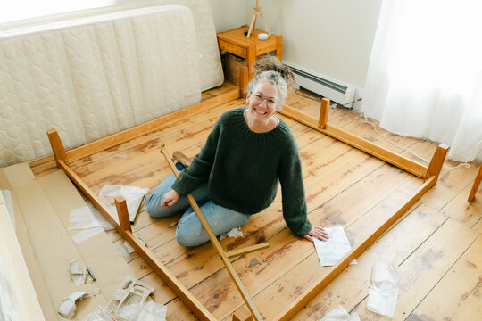 middle aged woman putting bed together 