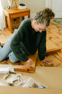 middle aged woman putting bed together 