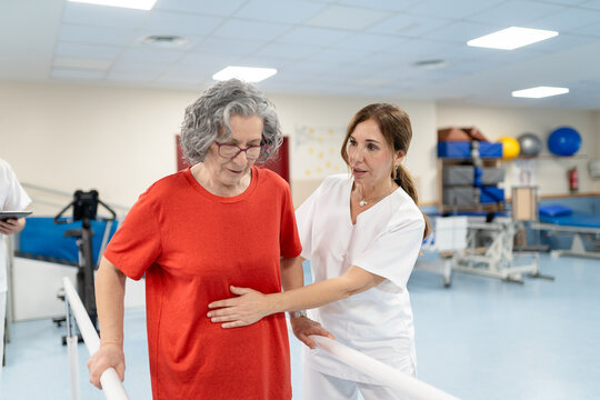 Senior woman doing physical therapy rehab walking in parallel bars
