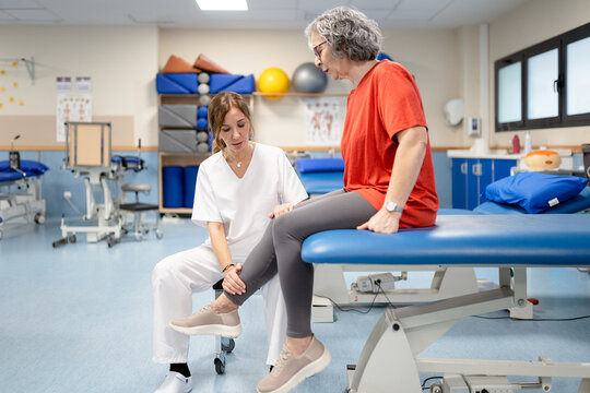 Physiotherapist assisting senior woman with leg exercise