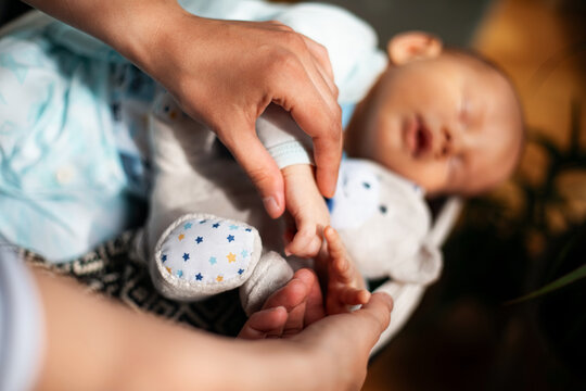 Parent Holding Newborn Baby Hand With Plush Toy