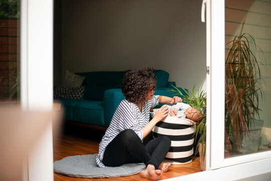 Mother Soothing Newborn Baby At Home In Living Room