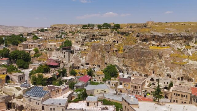 Urgup, Nevsehir, Turkey. Ancient rock dwellings and modern cave hotels carved into cliffs above contemporary city buildings, summer day.. Aerial View