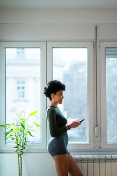 Woman using phone by large window in daytime