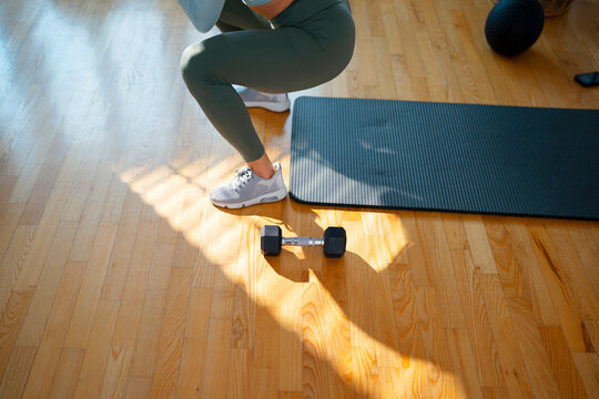 Person does squats in home gym with dumbbell