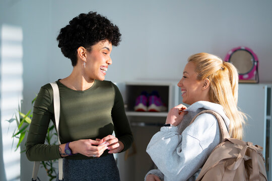 Two friends talk and smile in a bright room