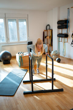 Woman exercises with dip bars in fitness space