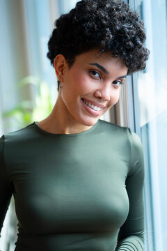 Smiling person standing by a window indoors