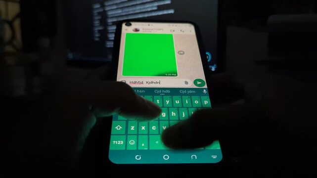 Close up view of hands fast typing random text on backlit smartphone keyboard in dark room environment showing digital communication interface during night hours with glowing screen illumination.