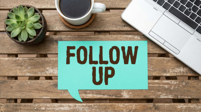 Follow up reminder on wooden desk with laptop coffee and succulent plant