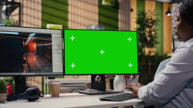 Green screen and video game software on dual monitors at the office, developer working with tools and assets to build a futuristic virtual world. Engineer developing gameplay mechanics.