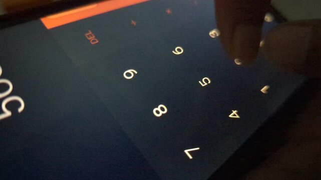 Person using digital calculator app on mobile phone screen to compute math numbers in dark environment close up view of fingers pressing buttons on touchscreen for business and finance tasks.
