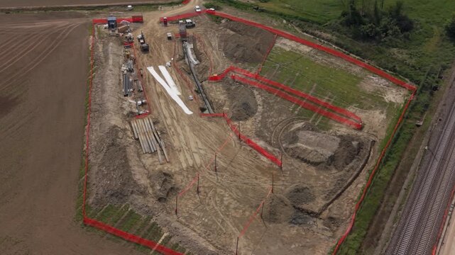 Construction Site Aerial View: An aerial perspective captures a busy construction site, showcasing excavators, heavy machinery, and temporary fencing demarcating the ongoing development.