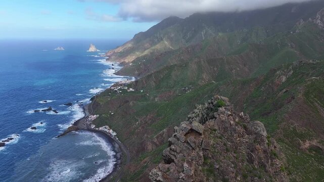 View from the summit of Roque de Las Animas cliff near the village of Taganana over the ocean coast and the village of Almaciga. Anaga Rural Park. Canary Islands. Tenerife. Aerial video. 4K 50fps.